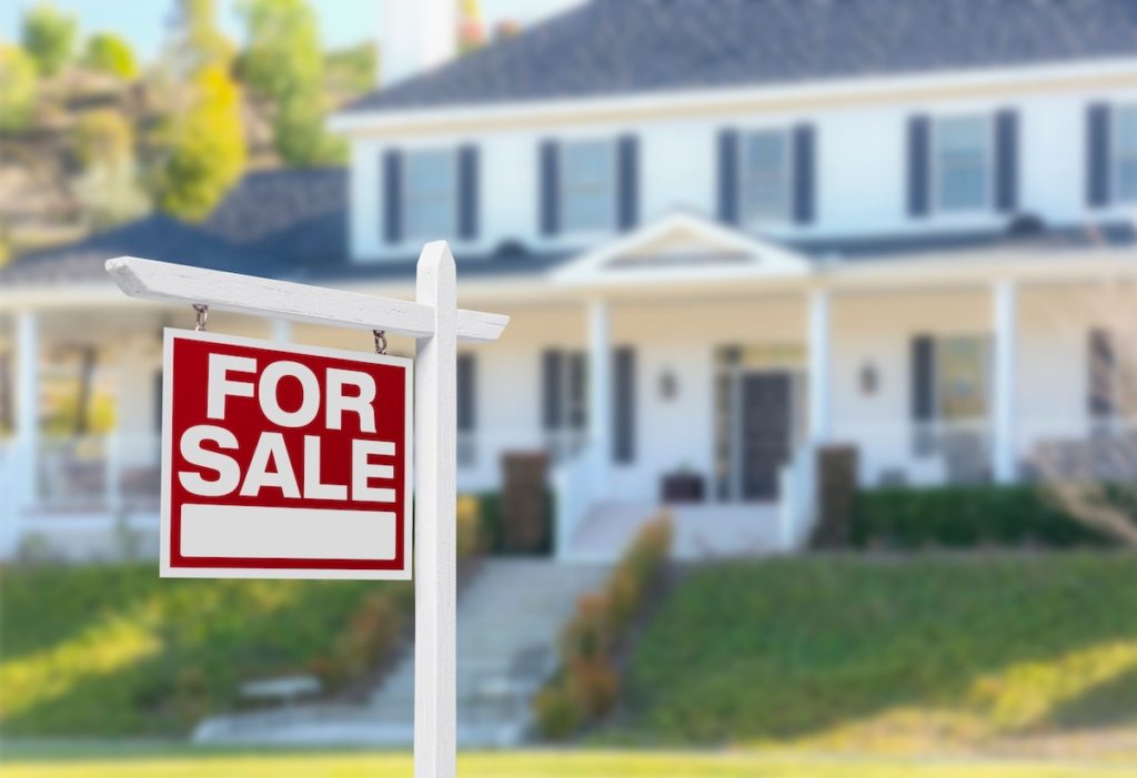 Home For Sale Real Estate Sign in Front of Beautiful New House.