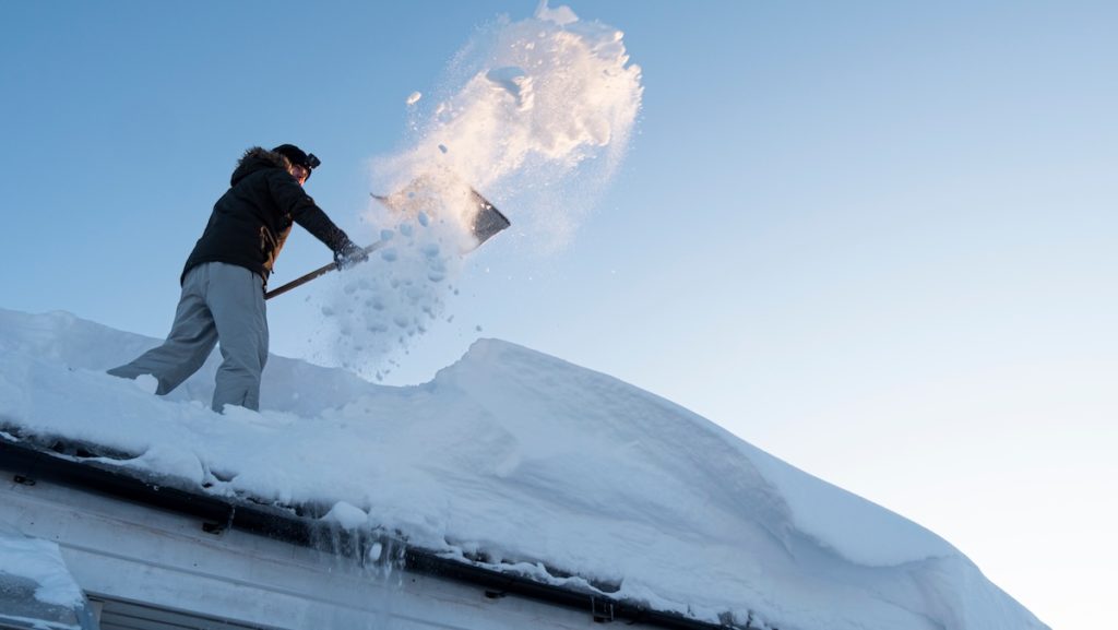 Man shoveling snow off roof